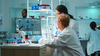 Bilim adamlarından oluşan bir ekip gece geç saatlerde bilgisayarda tartışıyor ve yazı yazıyor.