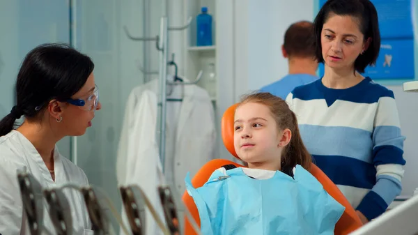 Закрыть пациента с зубной болью в зубном нагруднике, разговаривающего с дантистом — стоковое фото