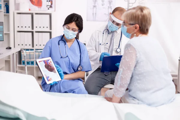 Enfermera explicando el diagnóstico cardíaco en cardiología a la mujer mayor en la tableta pc — Foto de Stock