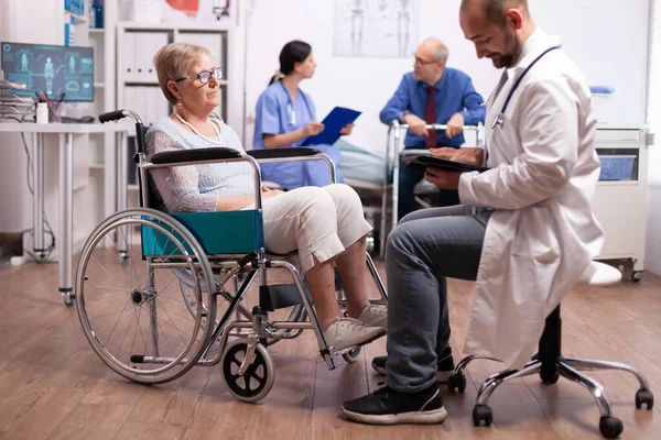 Медичний лікар, який обговорює з інвалідом старшою жінкою — стокове фото