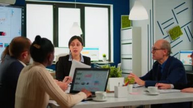 Çok ırklı iş adamları ofis merkezinde oturmuş proje hakkında konuşuyorlar.