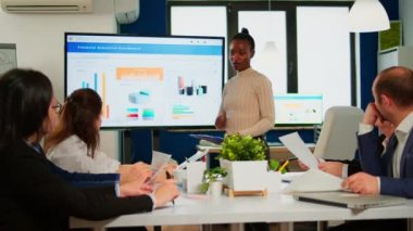 İş arkadaşlarının önünde şirket istatistiklerini açıklayan zenci kadın işçi.