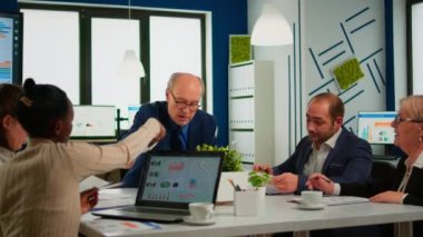 Kıdemli iş adamı takım lideri, iş arkadaşıyla kağıt işleriyle beyin fırtınası yapıyor.