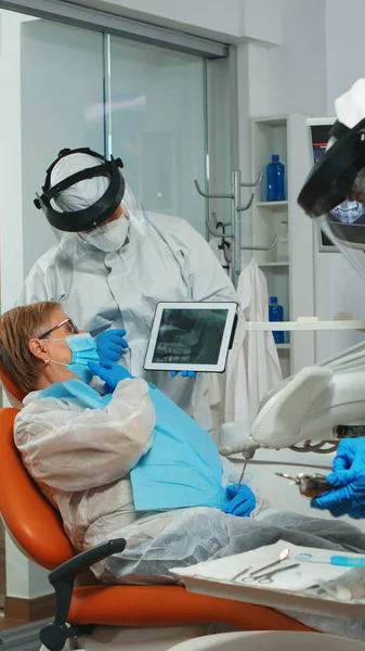 Zahnarzt in Overall zeigt auf Tablet zahnärztliche Röntgenaufnahme — Stockfoto