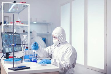 Otomatik pipetle kaplama giyinmiş bir mikrobiyolog.