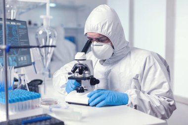 Mikroskopla çalışan erkek bilim adamı tedavi araştırması yapıyor.
