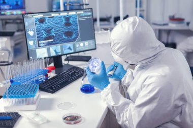 Virolog modern laboratuardaki petri kabında çözeltiyi inceliyor