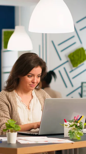 Donna d'affari soddisfatta che risponde alle e-mail digitando sul computer portatile sorridendo — Foto Stock