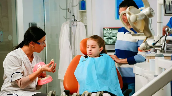 Стоматолог объясняет ребенку операцию с помощью гипсовой модели нижней челюсти — стоковое фото