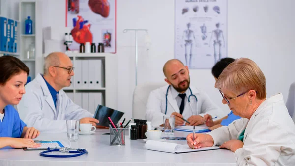 Médicos en reunión de personal sentados uno frente al otro hablando — Foto de Stock