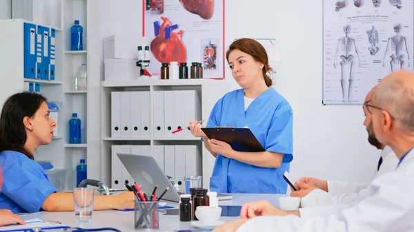 Team van artsen bespreken diagnose zitten aan tafel in kliniek — Stockfoto