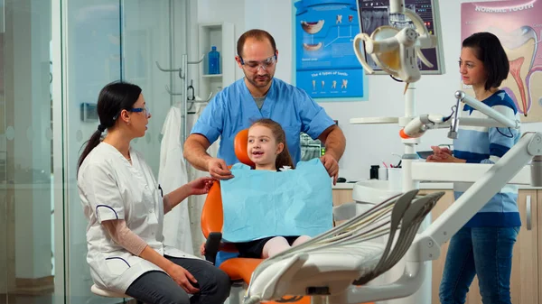 Pacjentka z bólem zęba wyjaśniająca stomatologowi dziecięcemu problem z zębami — Zdjęcie stockowe