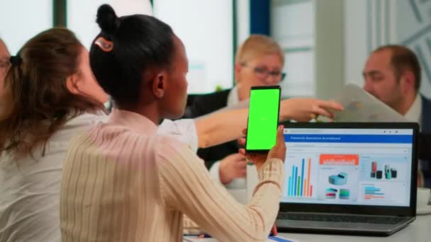 Konferans masasında oturan siyah iş kadını elinde yeşil ekranlı akıllı telefon tutuyor. — Stok video