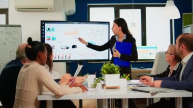 Finansal toplantı düzenleyen kadın proje yöneticisi istatistiksel grafikleri gösteriyor
