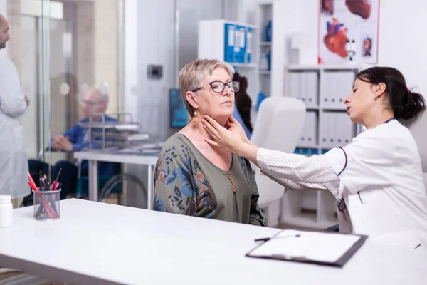 Professionele arts controleren nek lymfeklieren van oude vrouw — Stockfoto