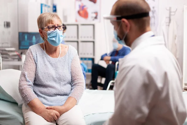 Mature patient speaking with medical staff about infection with covid19 — Stock Photo, Image