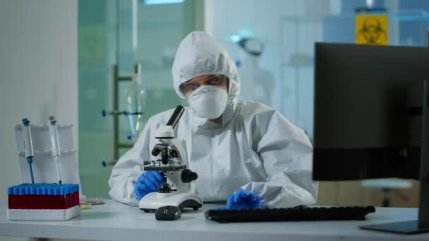 Lekarz biolog w okładce sprawdza próbkę DNA na mikroskopie — Wideo stockowe
