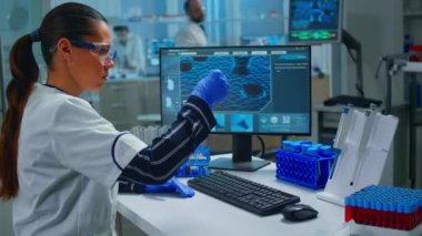 Kadın teknolojist bir laboratuvar testi yapıyor. Kan örneğiyle bir şişeyi inceliyor.