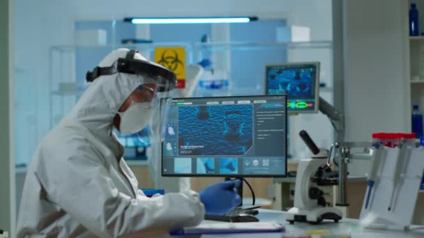 Vědec v ochranném obleku psaní na PC pracuje v lékařské laboratoři — Stock video