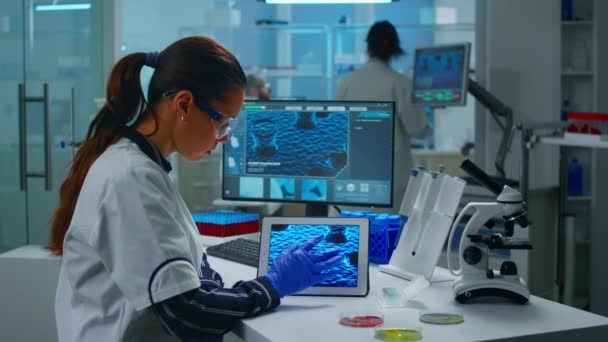 Técnico de laboratorio médico analizando la evolución del virus mirando en la tableta digital — Vídeos de Stock