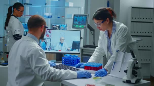 Лабораторні техніки розмовляють по відеозв'язку з професійним лікарем-хіміком — стокове відео