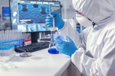 Kimya mühendisi mikro pipet ve petri kabı üzerinde deneyimler yürütüyor.