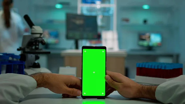 Pov záběr mikrobiologa držícího telefon se zeleným displejem s klíčem chroma — Stock fotografie