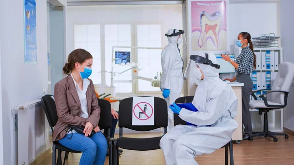 Медсестра-стоматолог с защитным оборудованием разговаривает с пациентом — стоковое фото
