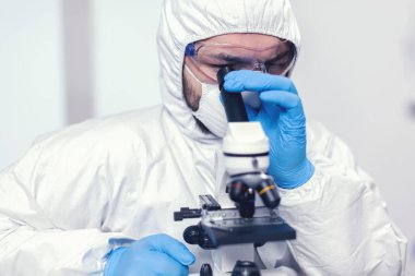 Virüs örneğine mikroskopla bakan tıbbi araştırmacı