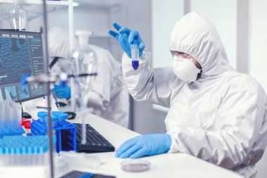Laboratuar araştırmacıları test tüpündeki numuneye yakından bakıyor.