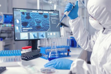 Biyokimyacı, elinde otomatik pipetle sıvı örneği alıyor.