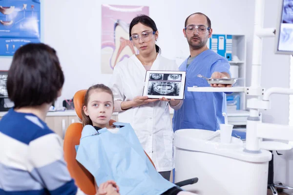 Pediatric dentist discussing about cavity prevention with parent of little girl — Stock Photo, Image