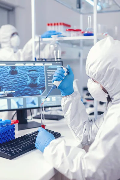 Ученый берет образец крови из пробирки с помощью микропипетки — стоковое фото