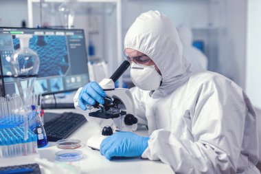 Sağlık kimyageri cam parçasındaki örneğe bakıyor.