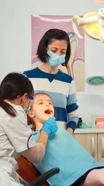 Técnico dentista com luvas explicando o processo para o paciente criança — Fotografia de Stock