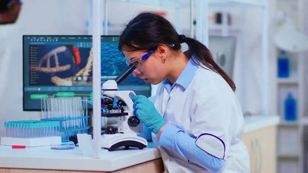 Donna scienziata con microscopio esaminando campioni e liquido — Foto Stock