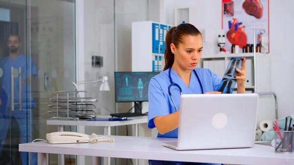 Femme infirmière médicale tenant patient radiographie dactylographie sur ordinateur portable — Photo