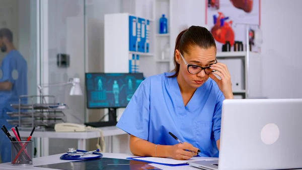 Exhausted therapist working on laptop and taking off the glasses — Stock Photo, Image