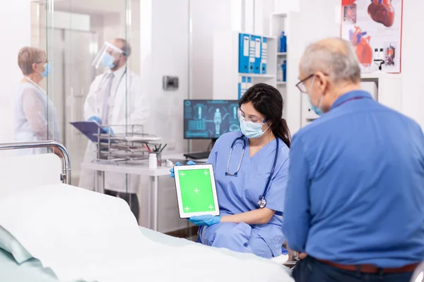 Paciente olhando para tablet com tela verde durante a consulta — Fotografia de Stock