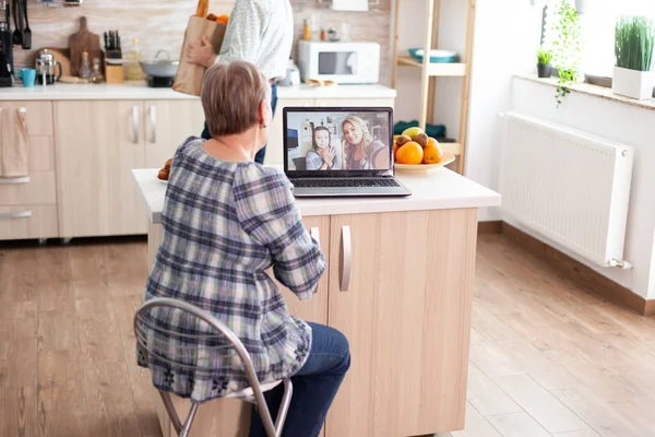 Enthusiastic senior woman talking with family online using laptop webcam — Stock fotografie