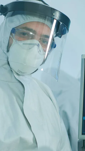 Microbiologist in ppe suit standing in laboratory looking at camera