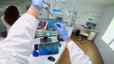 Laboratuvarda mikropipet kullanan bilim adamlarının POV 'u test tüplerinden mavi likit çıkarıyor.