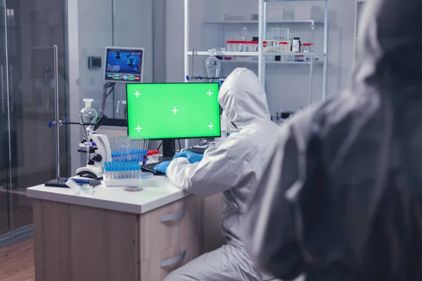 Scientist dressed in ppe suit working on computer