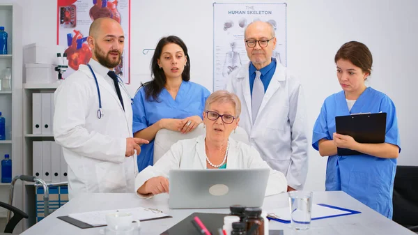 Doctors in lab coats working in hospital office discussing symptoms of disease