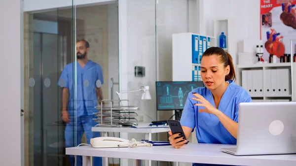 Nurse holding smartphone talking to patient making telemedicine
