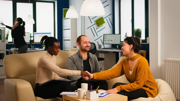 Consultant greeting diverse business clients with handshake