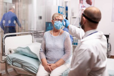 Sıhhiye kıdemli hastanın sıcaklığını kontrol etmek için dijital termometre kullanıyor