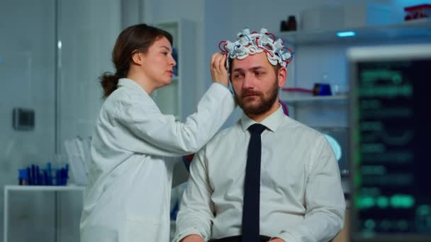 Paciente com fone de ouvido de varredura de ondas cerebrais sentado em laboratório de estudo cerebral — Vídeo de Stock