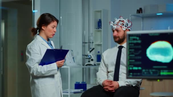 Homme assis sur une chaise neurologique avec casque à balayage d'ondes cérébrales — Video