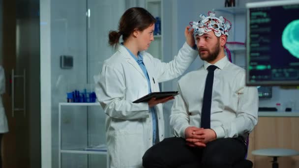 Человек, сидящий на неврологическом стуле с наушниками сканирования мозговых волн — стоковое видео